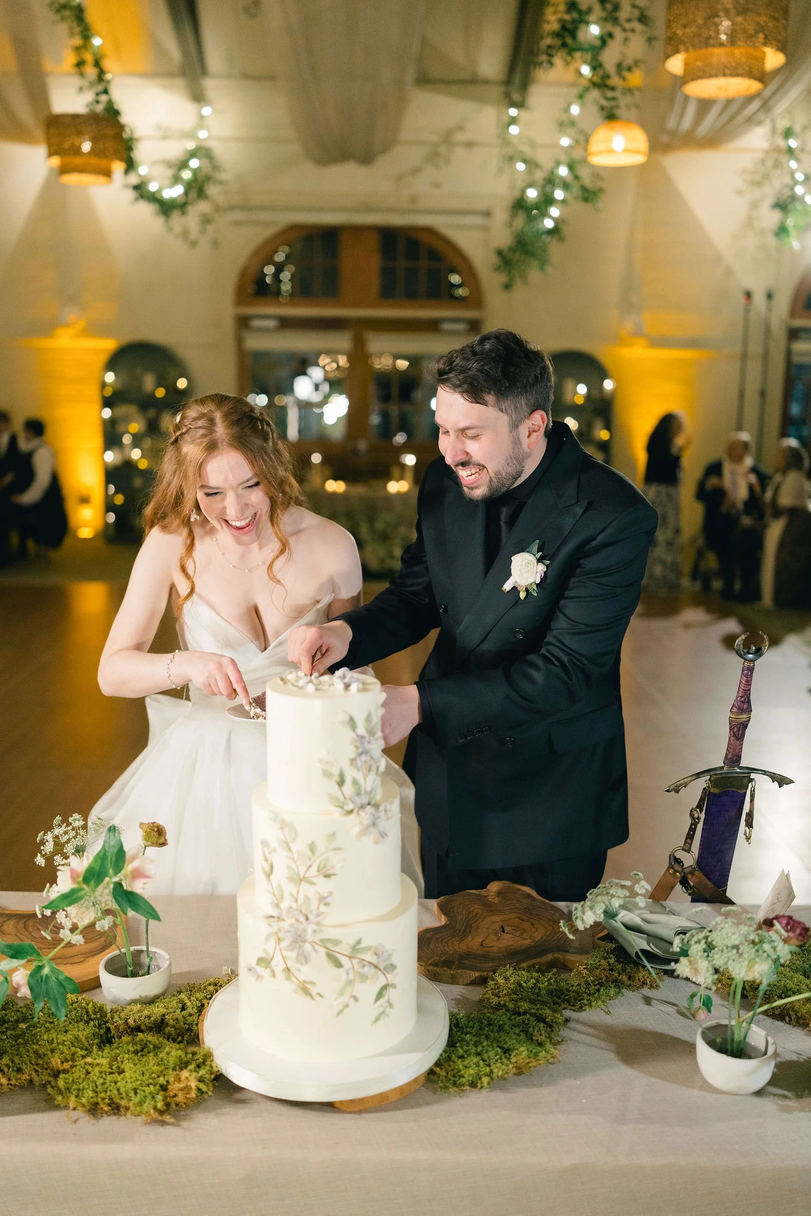Wedding couple cutting their wedding cake with a sword during their Elm Bank reception.