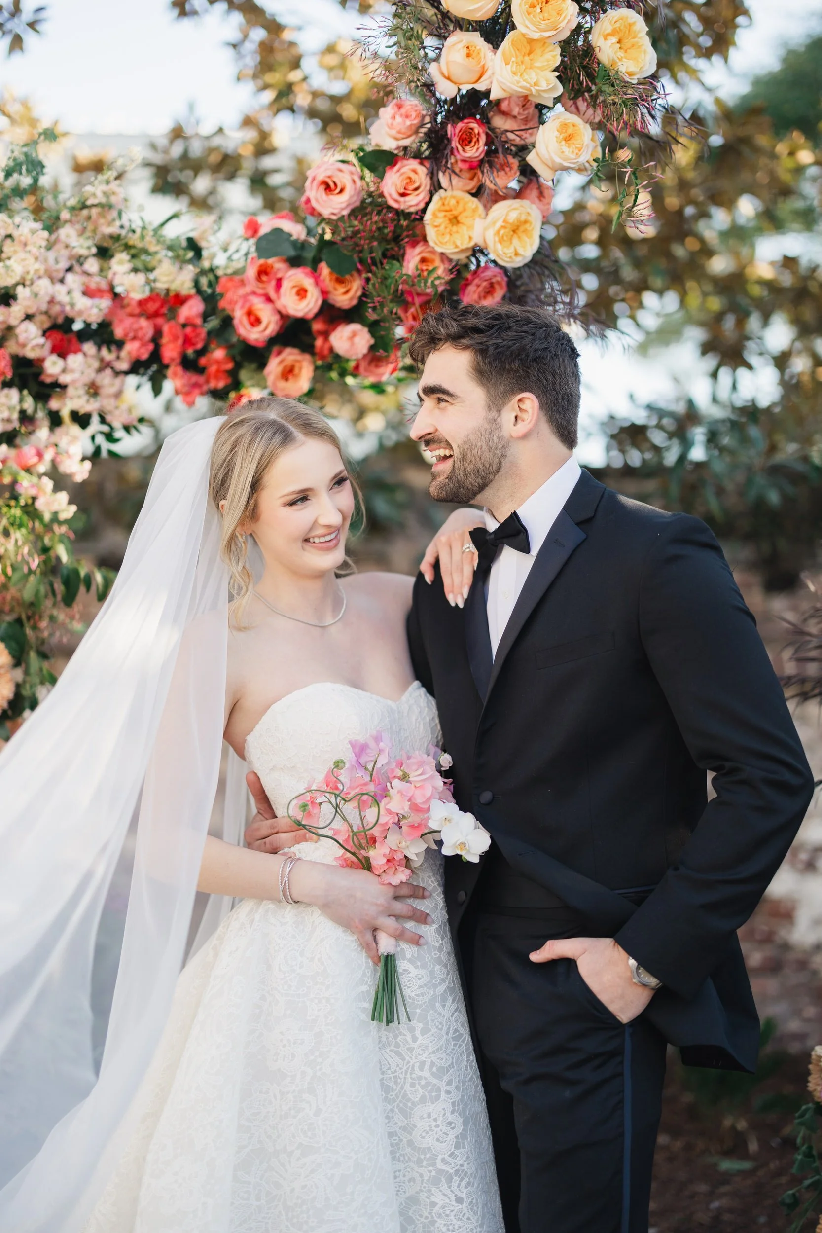 Romantic wedding portrait framed by cascading pink blooms in Charleston, SC