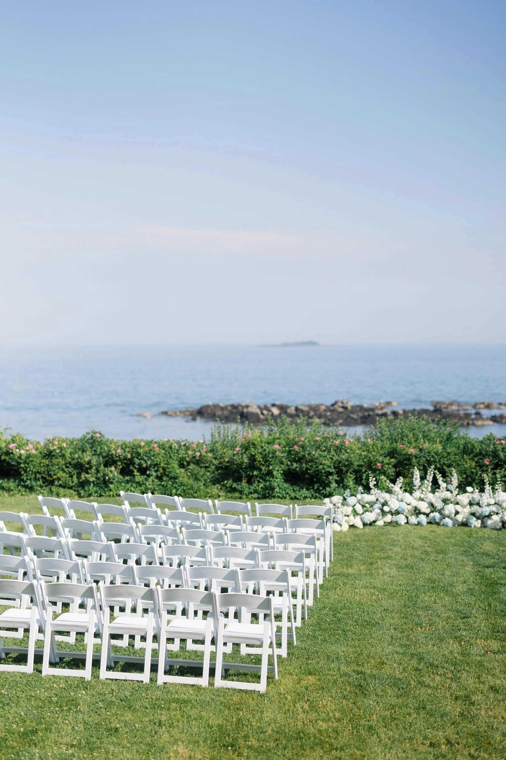 Elegant wedding ceremony setup with coastal views and summer florals.