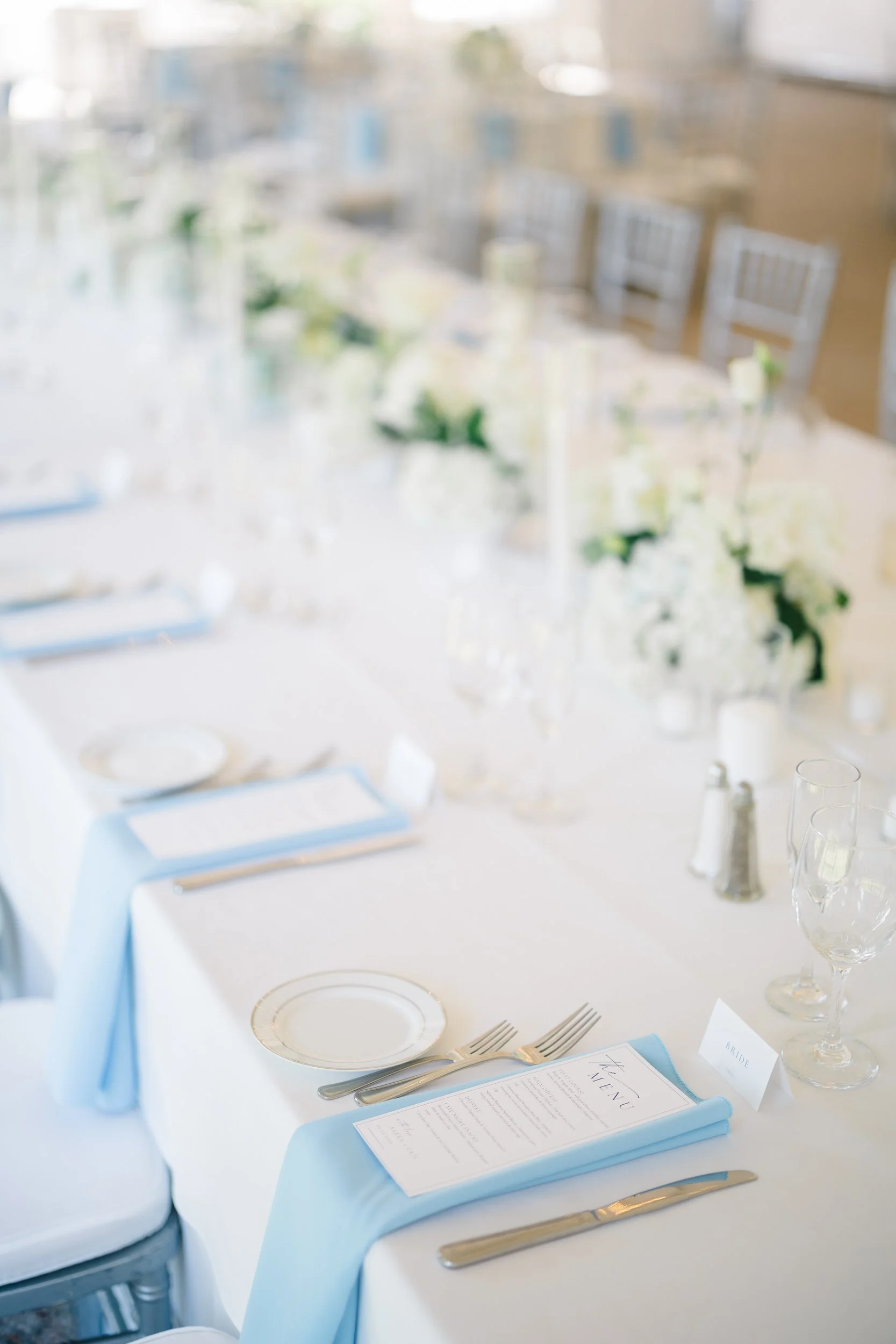 Reception tablescape with soft blue accents and seasonal summer flowers.