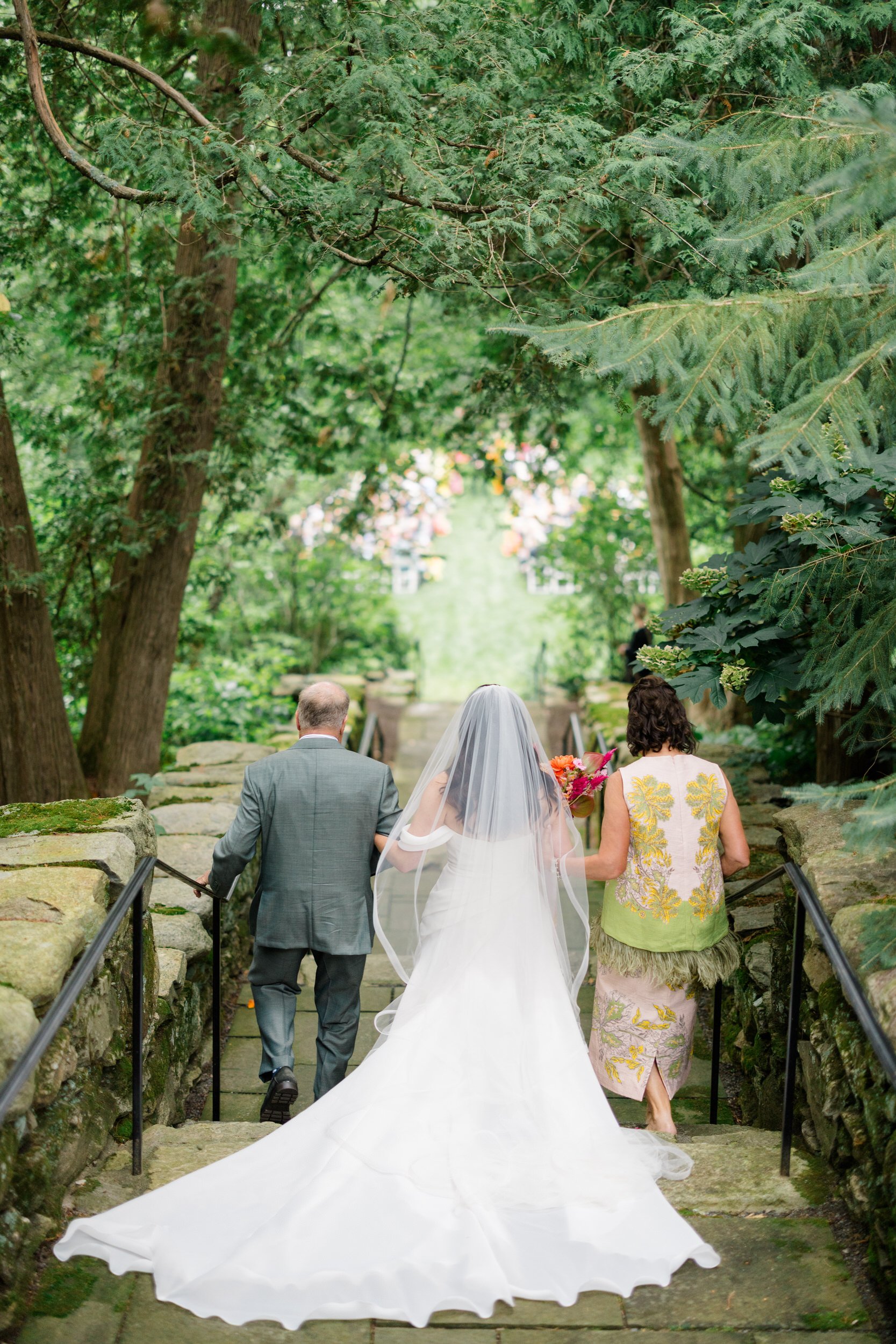 Bride walking down the aisle through a whimsical secret garden ceremony filled with colorful flowers.