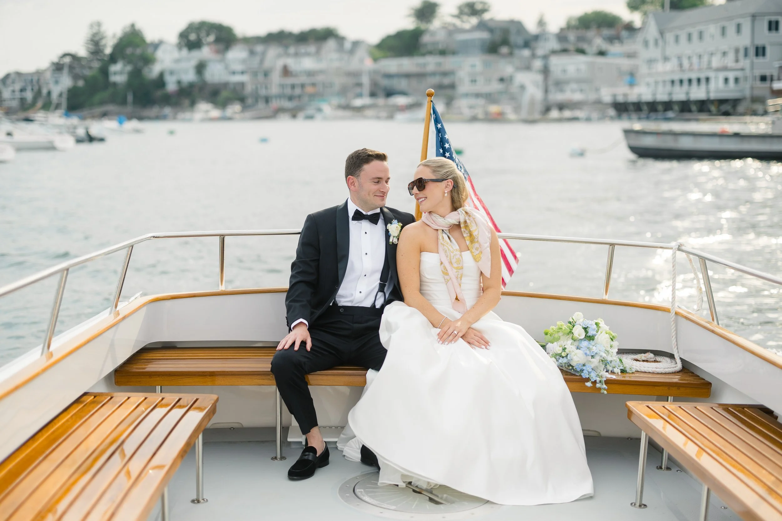 Romantic wedding portraits on a boat in Marblehead, Massachusetts overlooking a sail-filled harbor at sunset.