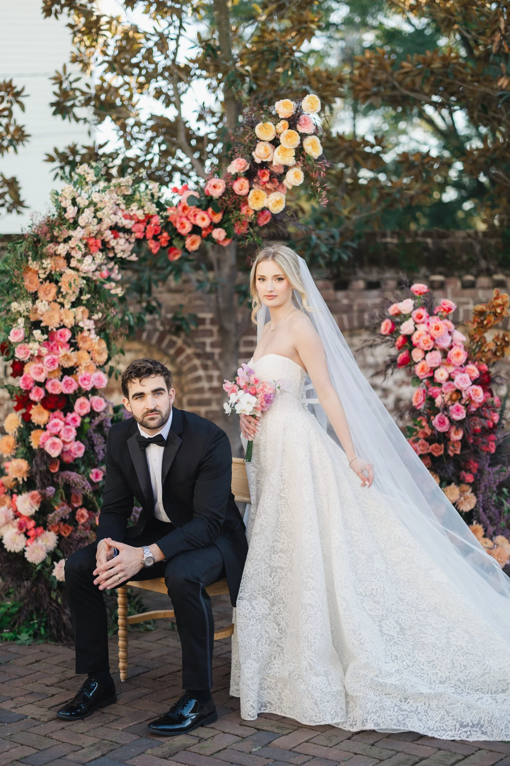 Bride and groom standing at their ceremony altar surrounded by vibrant spring florals.