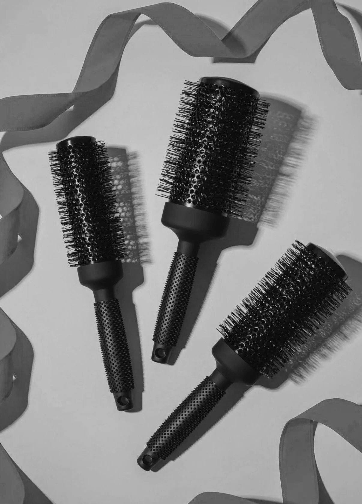 3 Ergo brand round brushes with a white background and a ribbon encircling