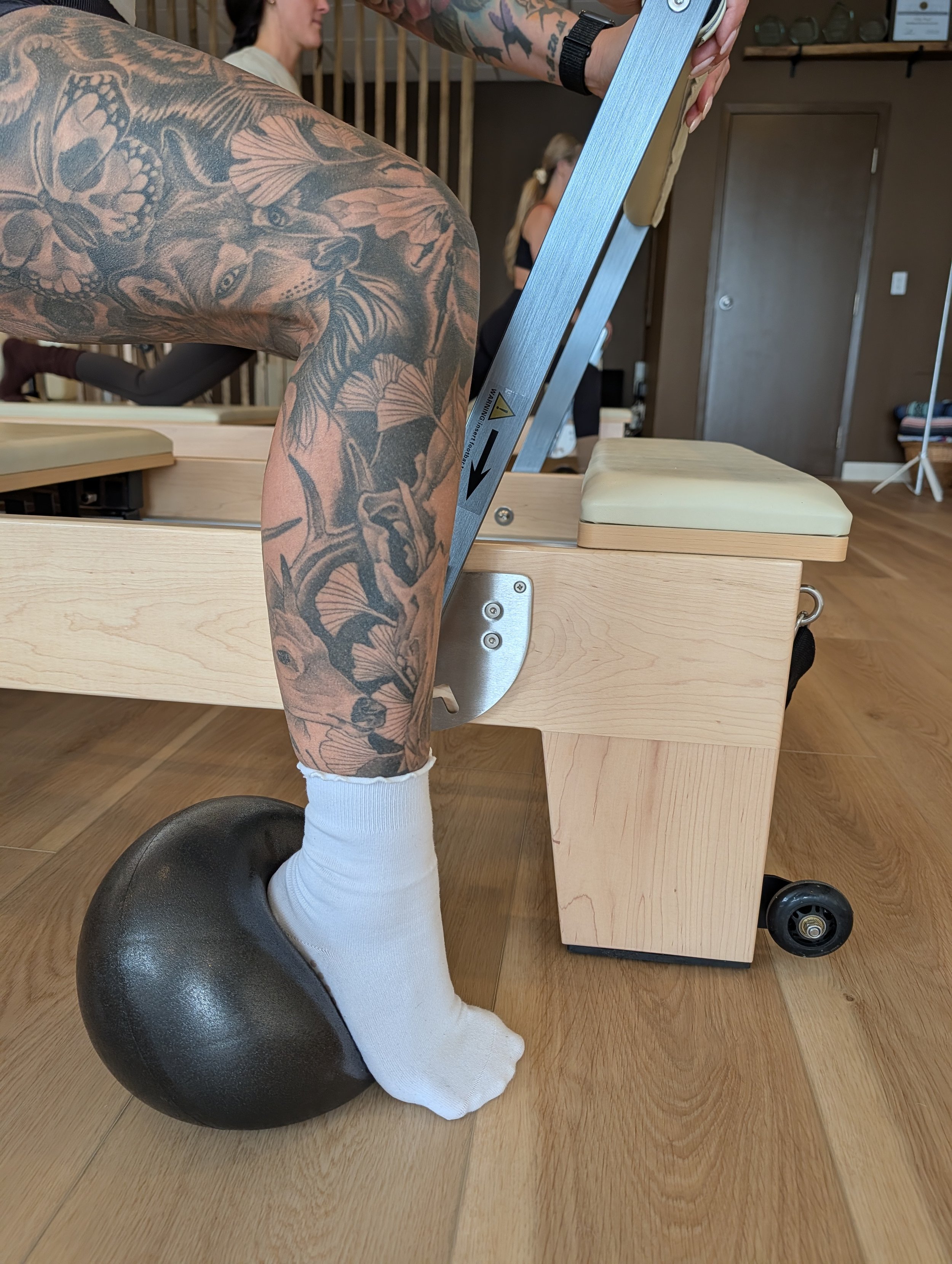 Individual in lunge position on reformer with heel on ball