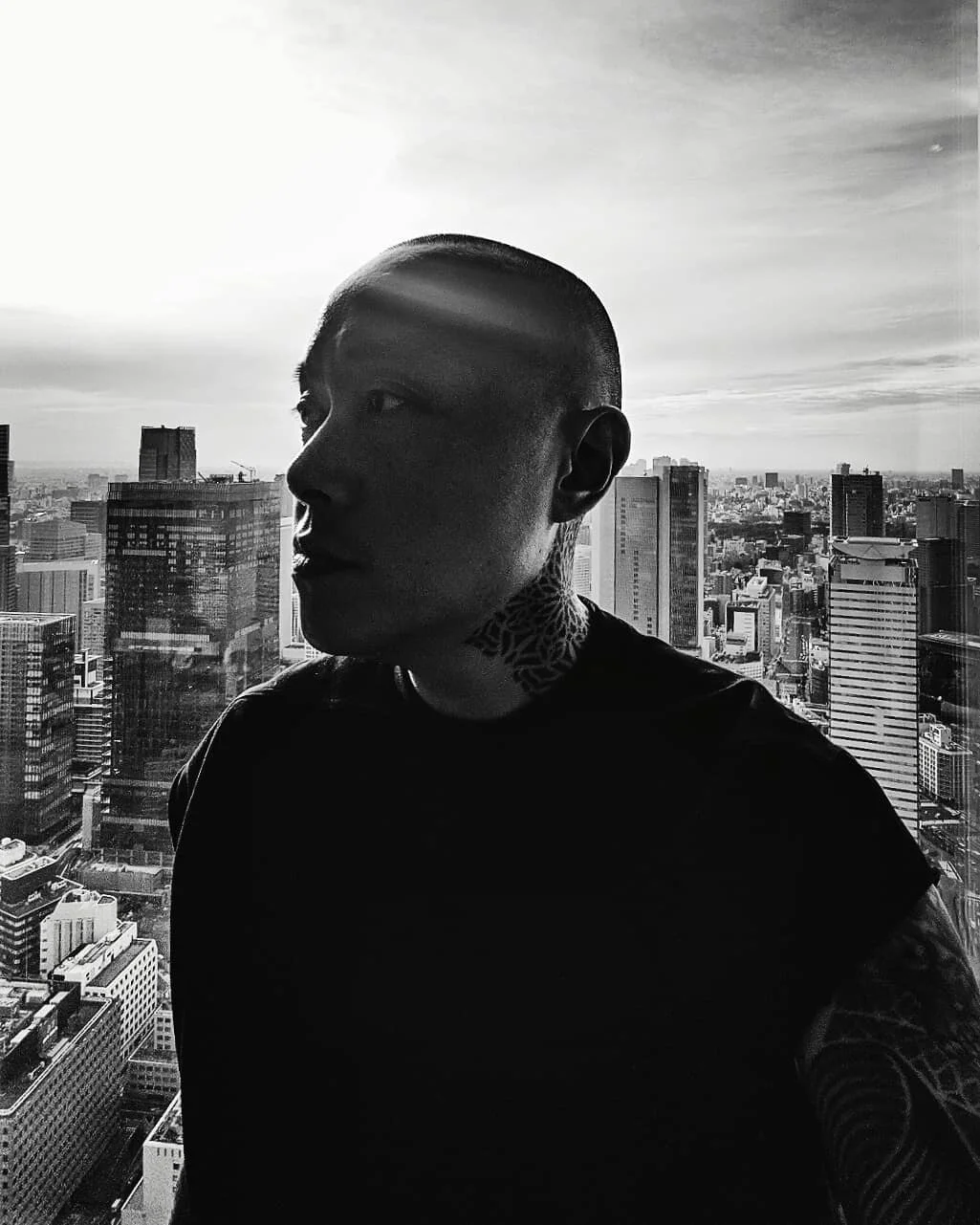 Black-and-white portrait of Kenny Rufino, Creative Director, against the Tokyo skyline