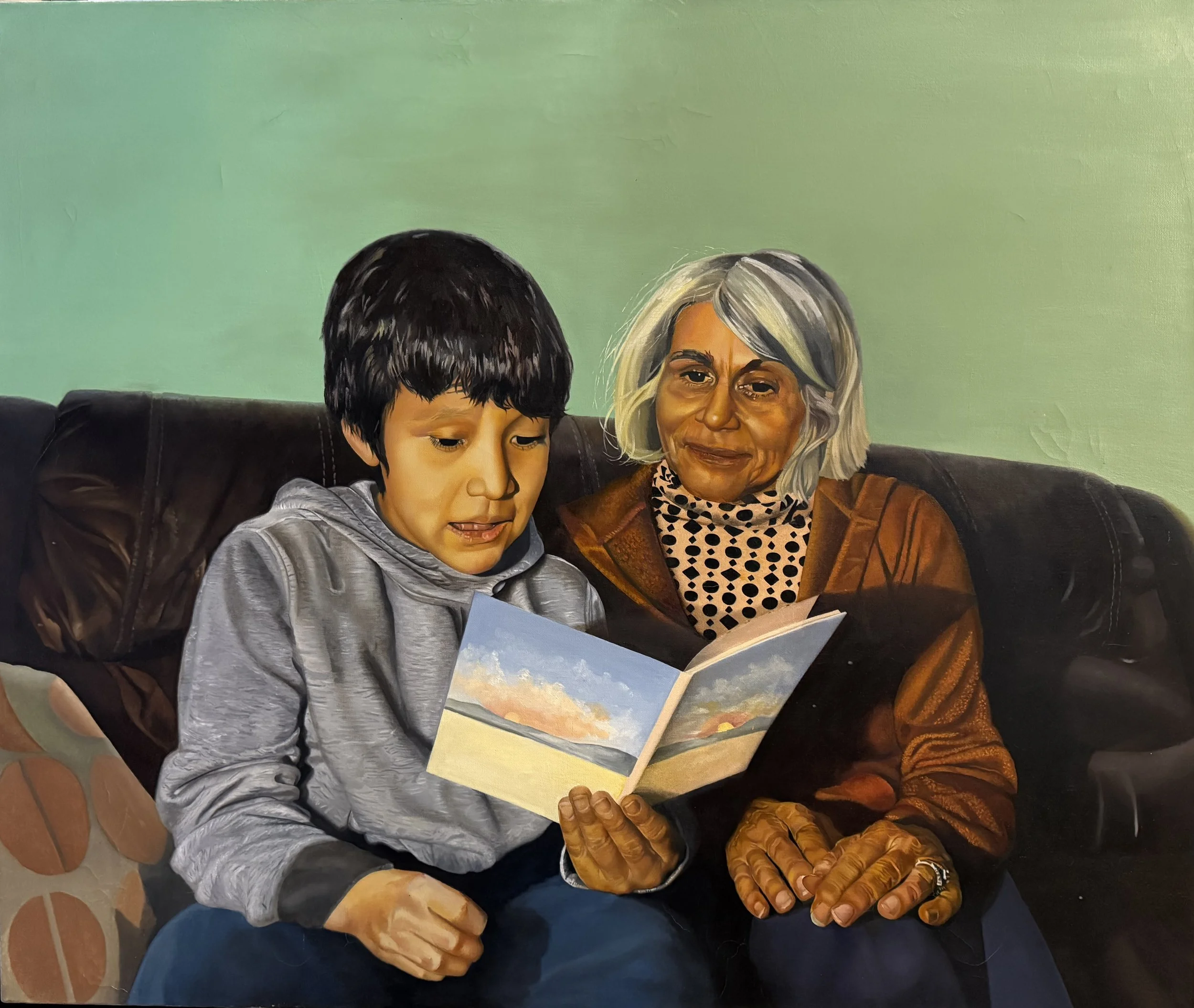 A painting of a young boy and an older woman sitting together on a sofa, reading a picture book with a landscape scene. The boy has dark hair and wears a gray hoodie, while the woman has gray hair, wears a brown jacket and patterned scarf, and has glasses. They are sitting closely against a green background.