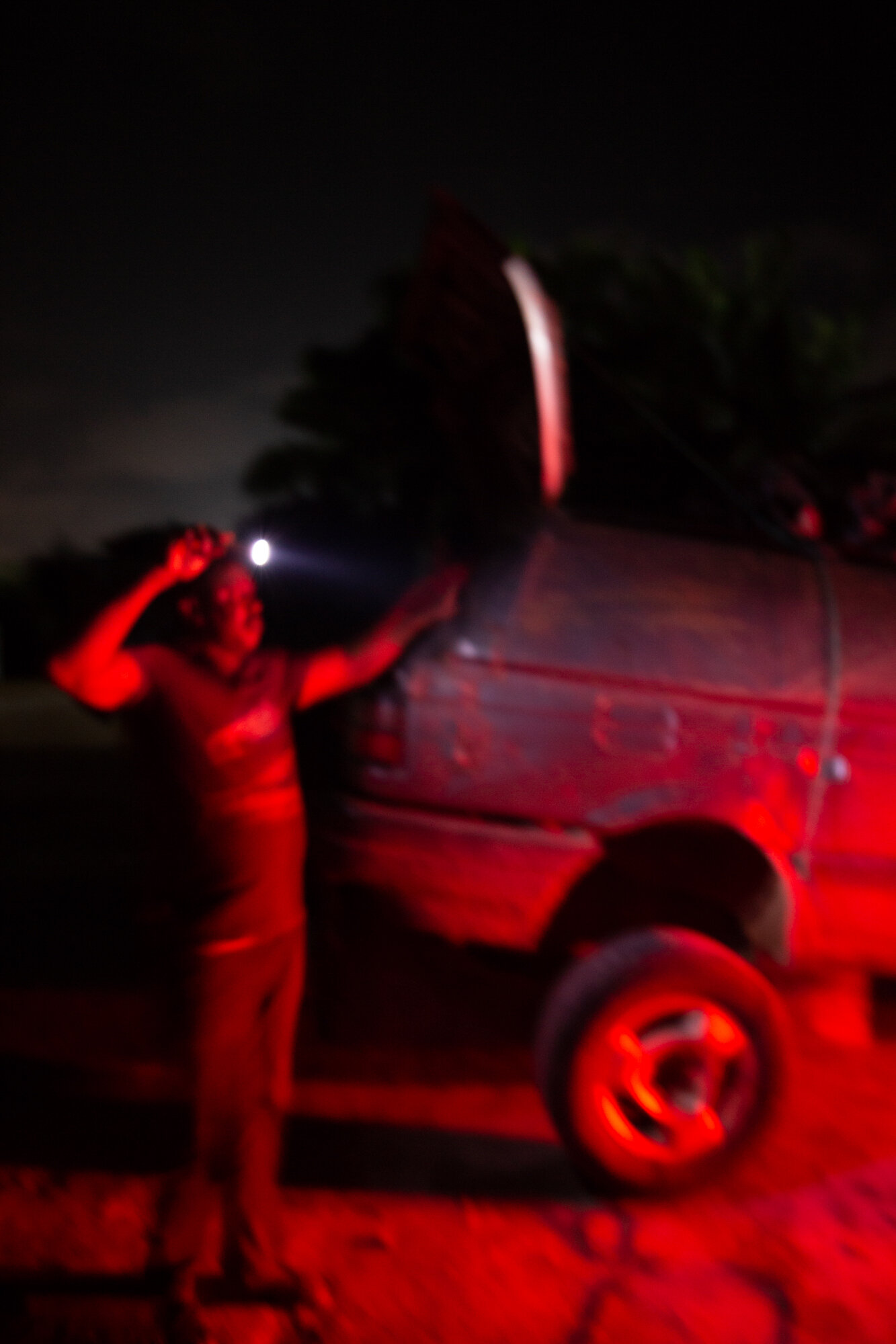 A man signals driver that bring goods to the park at night with a torch light. Most of the time drivers that bring good to this park usually miss their way