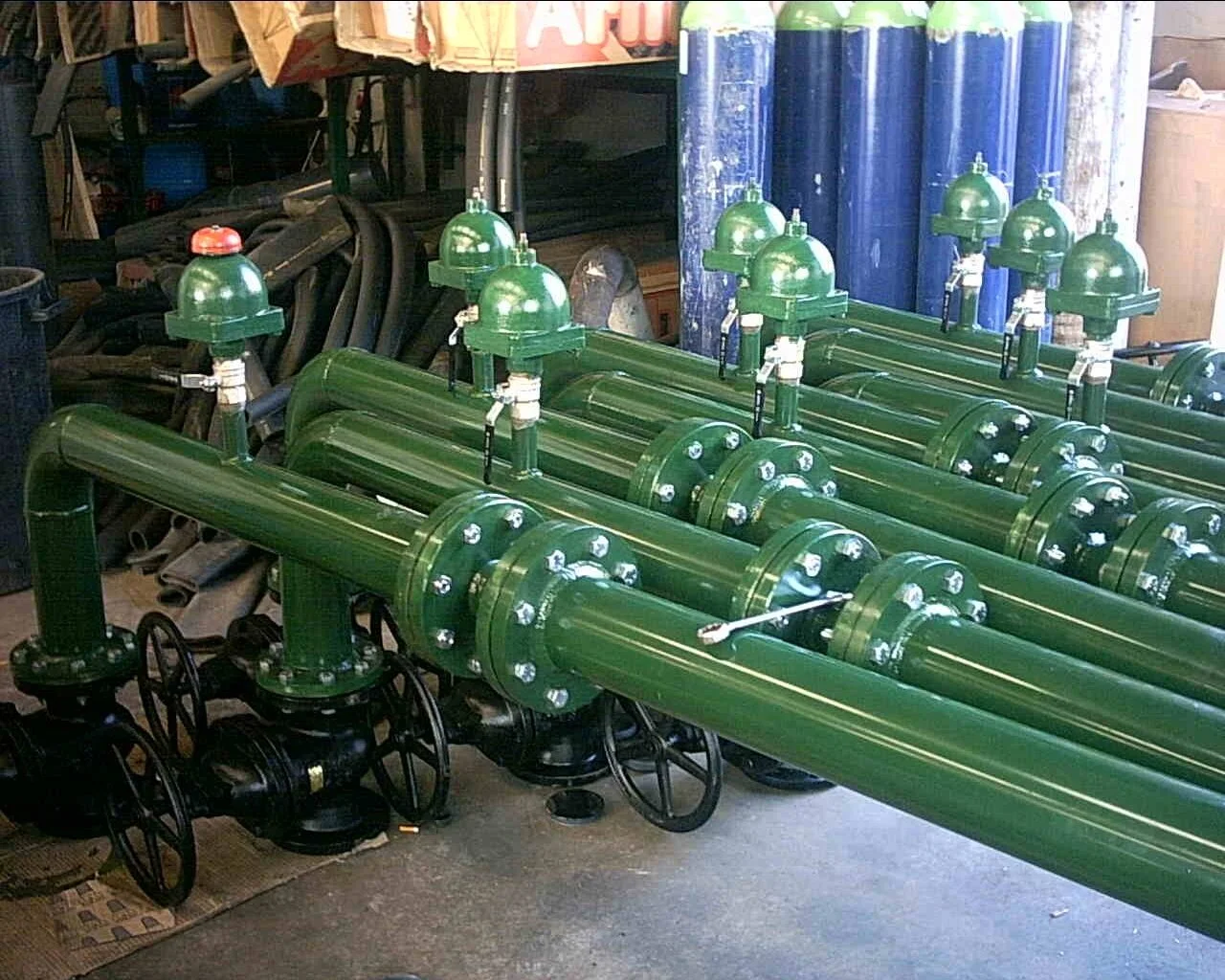 Gruppo di valvole e tubi verdi, probabilmente parti di un impianto industriale o idraulico.