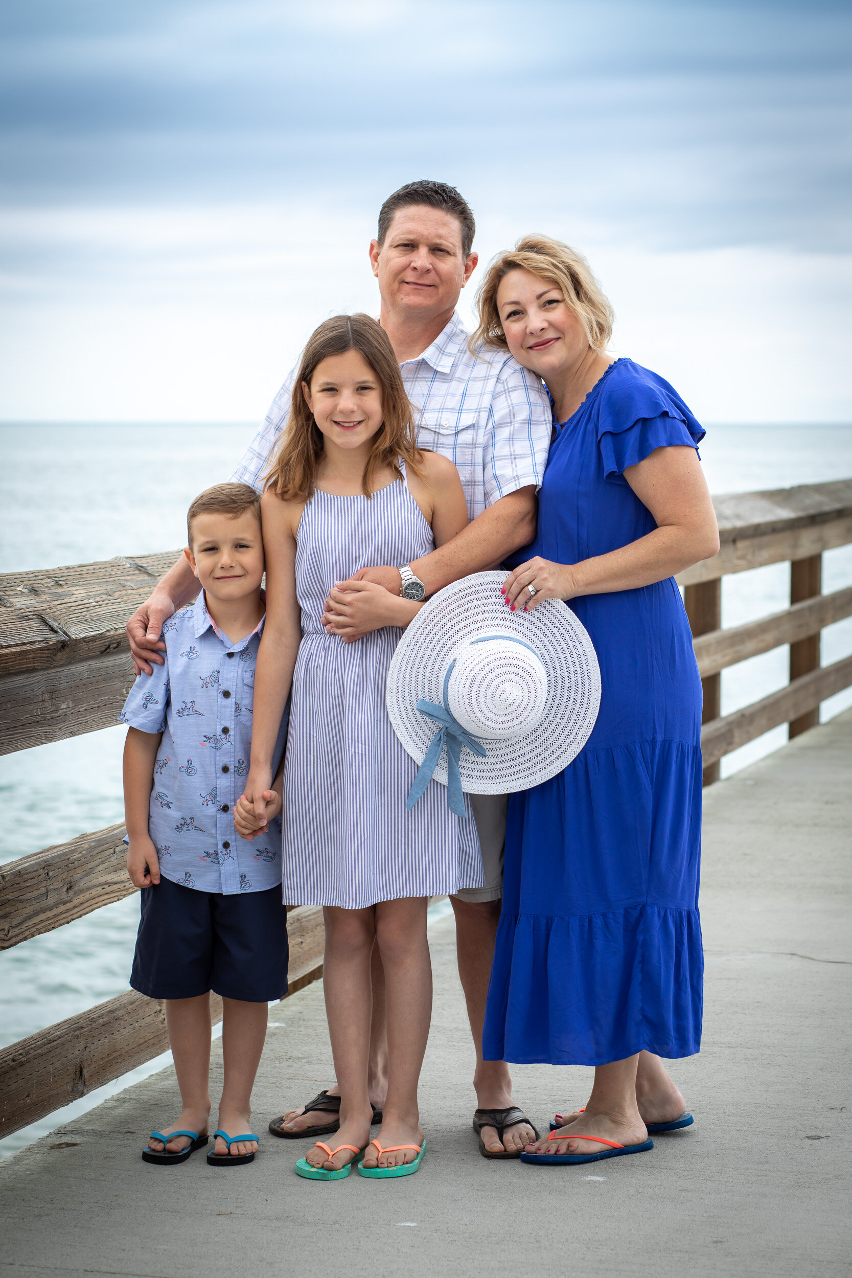Family-of-four-on-Newport-Beach-pier-holding-hat.jpg