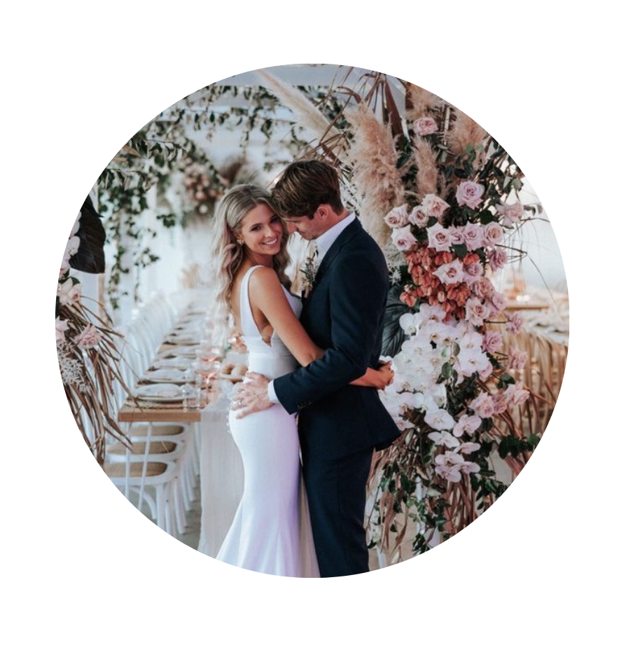 A bride and groom dancing under a floral arch at their wedding reception.