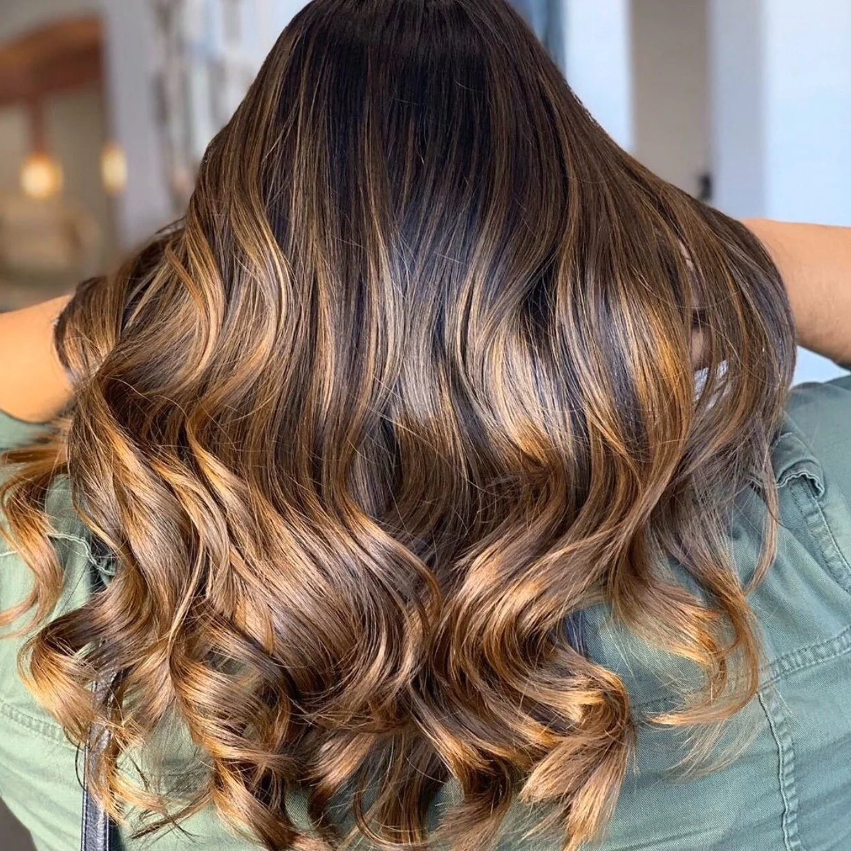 Brunette balayage with caramel ribbons and loose curls through the lengths.
