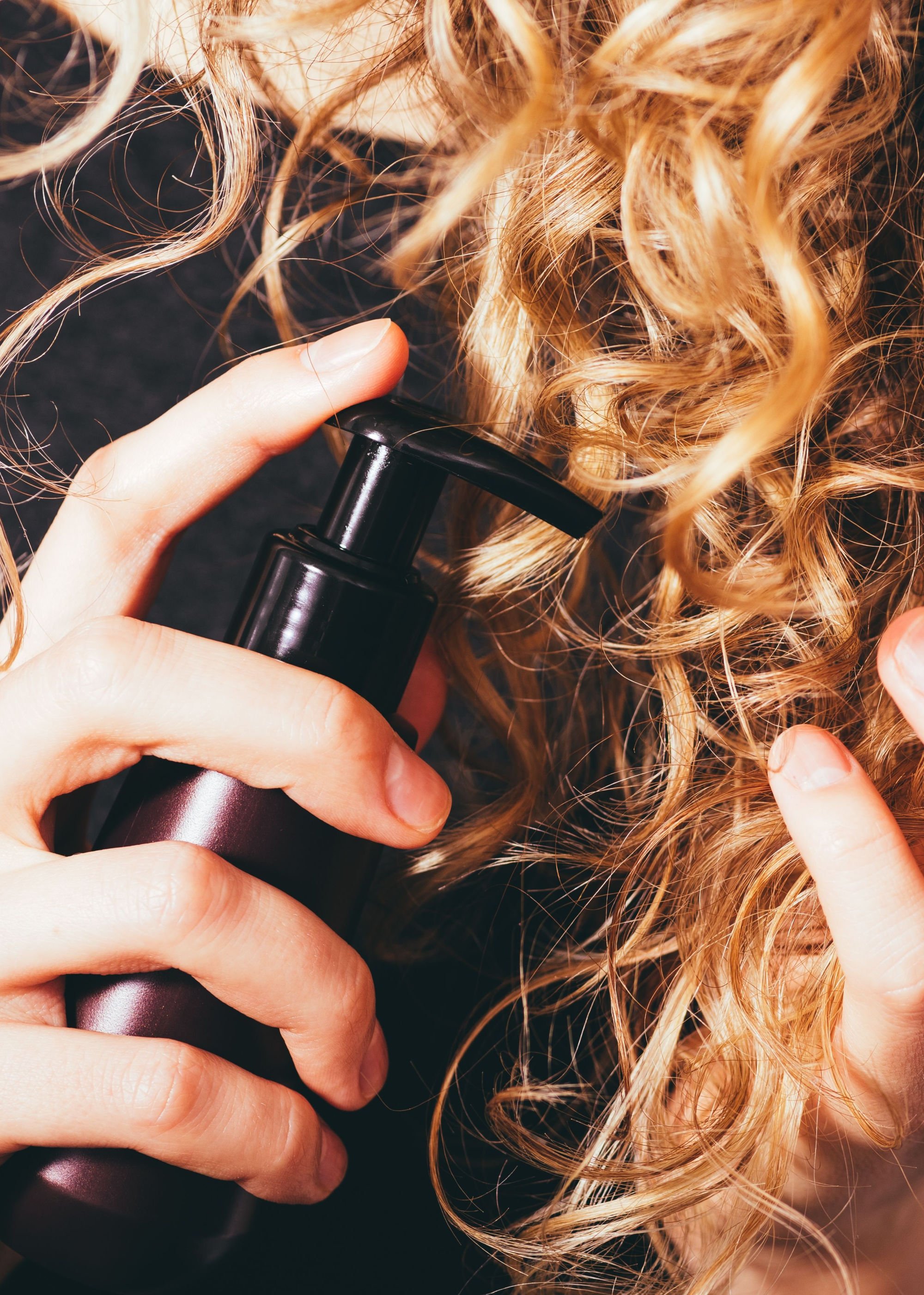Applying hair rebuilding and strengthening leave-in conditioning treatment to blonde curly hair