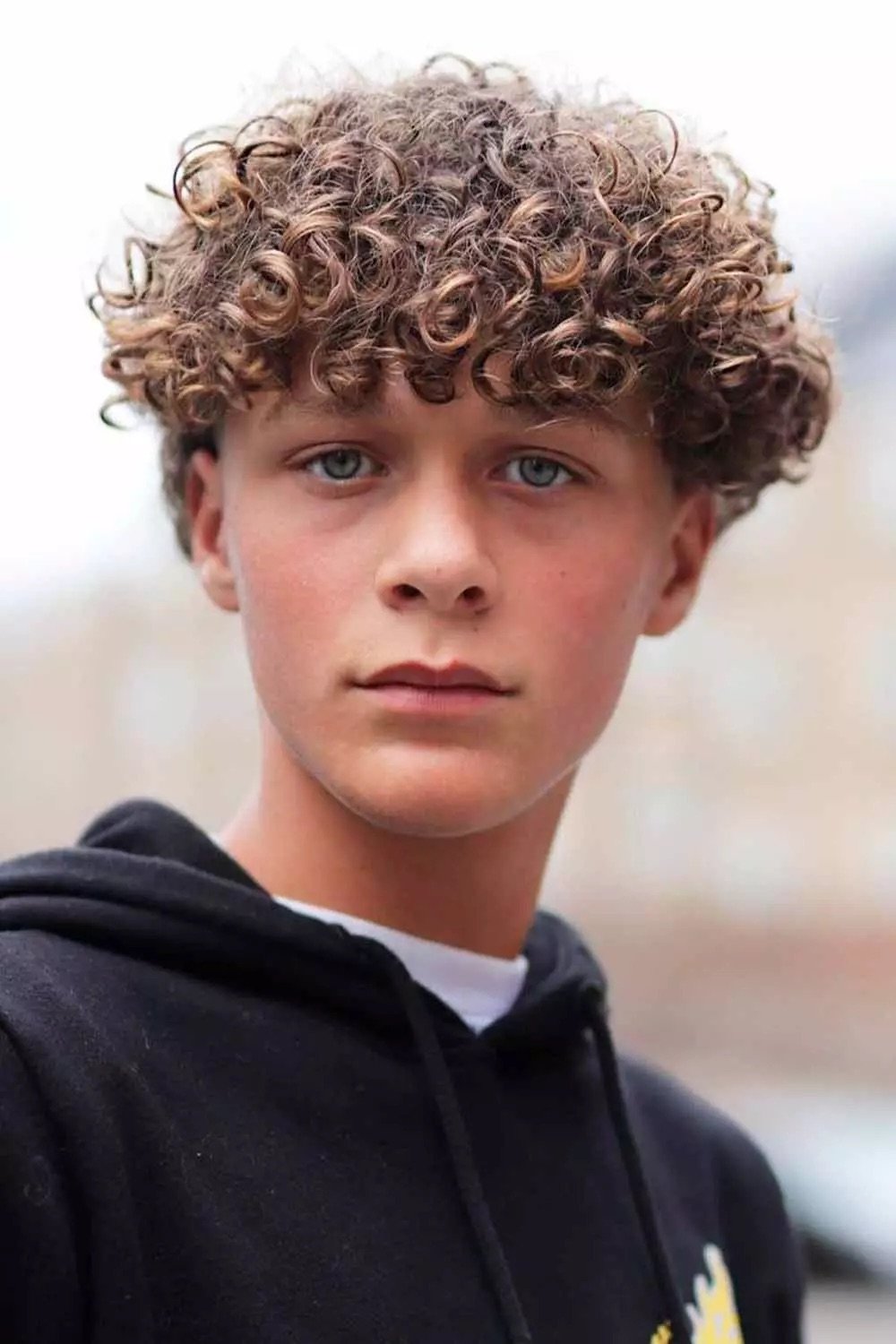Men's curly perm with textured curls and highlights