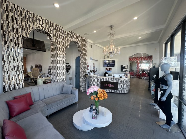 Reception and waiting lounge at Le Rêve Salon and Spa, with a gray sofa, red cushions and chandelier.