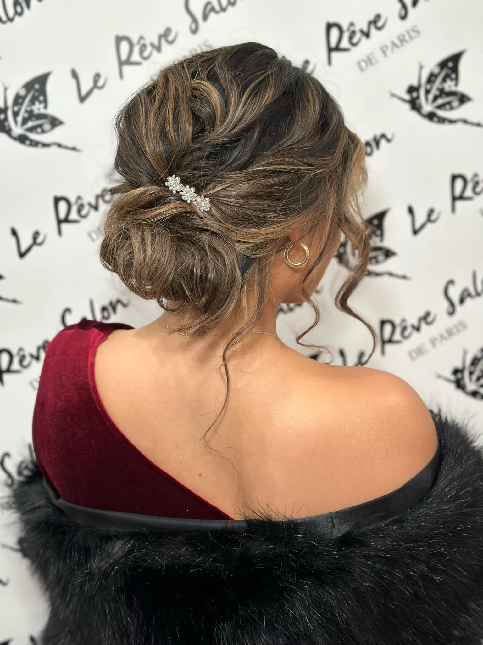 Elegant low bun updo with face-framing curls and crystal pin for weddings and events
