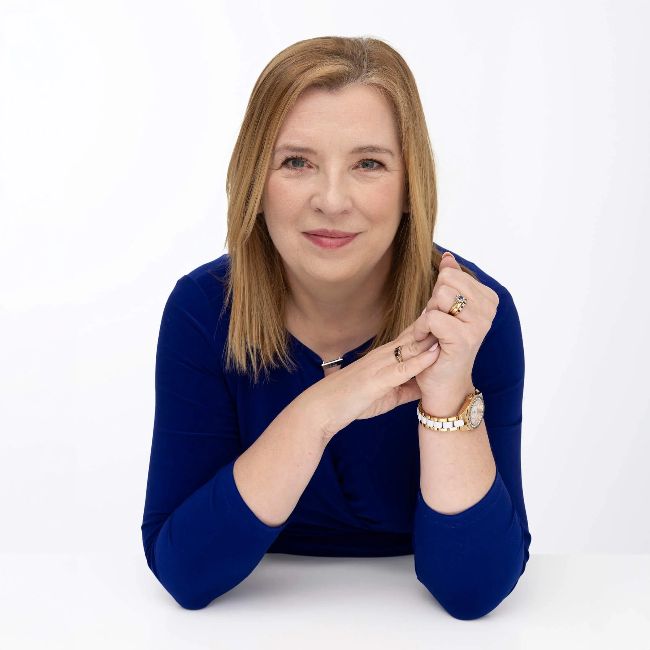 Maureen McCowen, public speaking coach and presentation skills trainer based in Ireland, wearing a cobalt blue top, leaning forward with a warm smile — helping professionals and teams build speaking confidence.