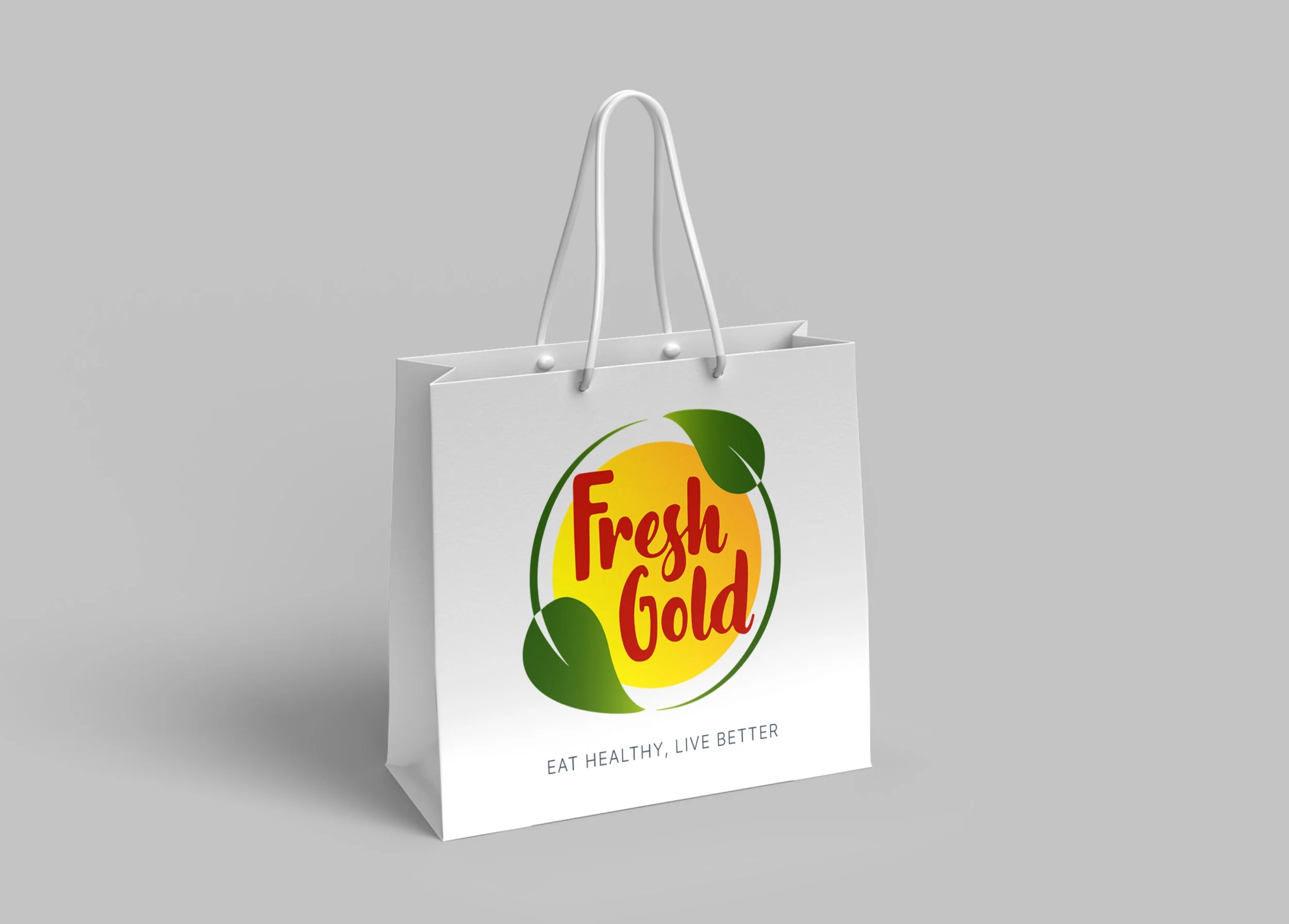 White grocery bag with 'Fresh Gold' logo, featuring a yellow circle and green leaves, and text 'Eat healthy, live better' at the bottom.