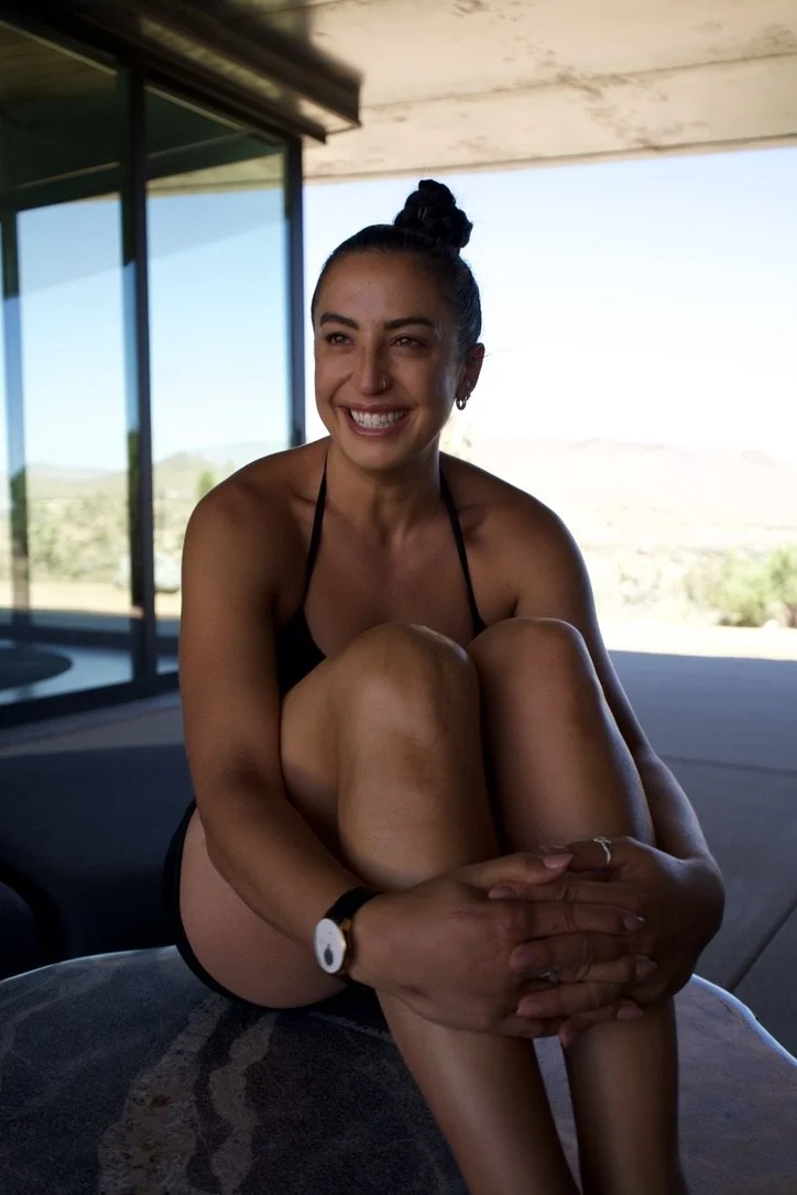 smiling young woman with her hands interlocked across her legs