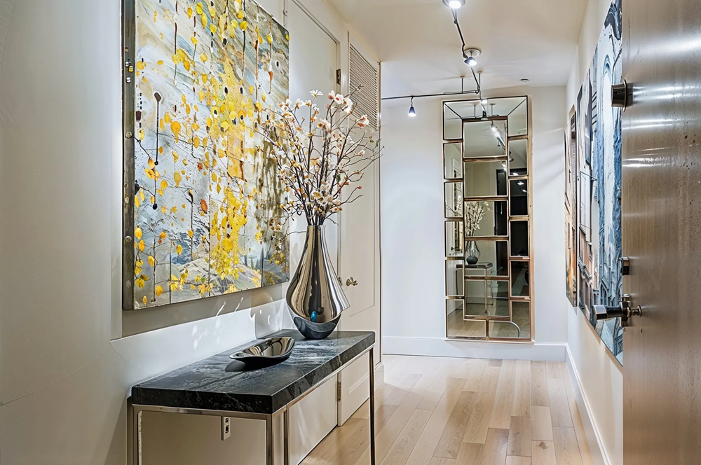 Modern hallway with abstract artwork, console table, and gold framed mirror.