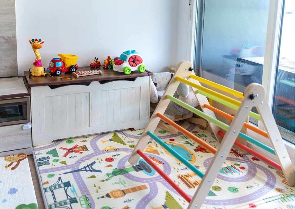 Bright indoor play corner with toy cars, activity rugs, and a climbing frame.