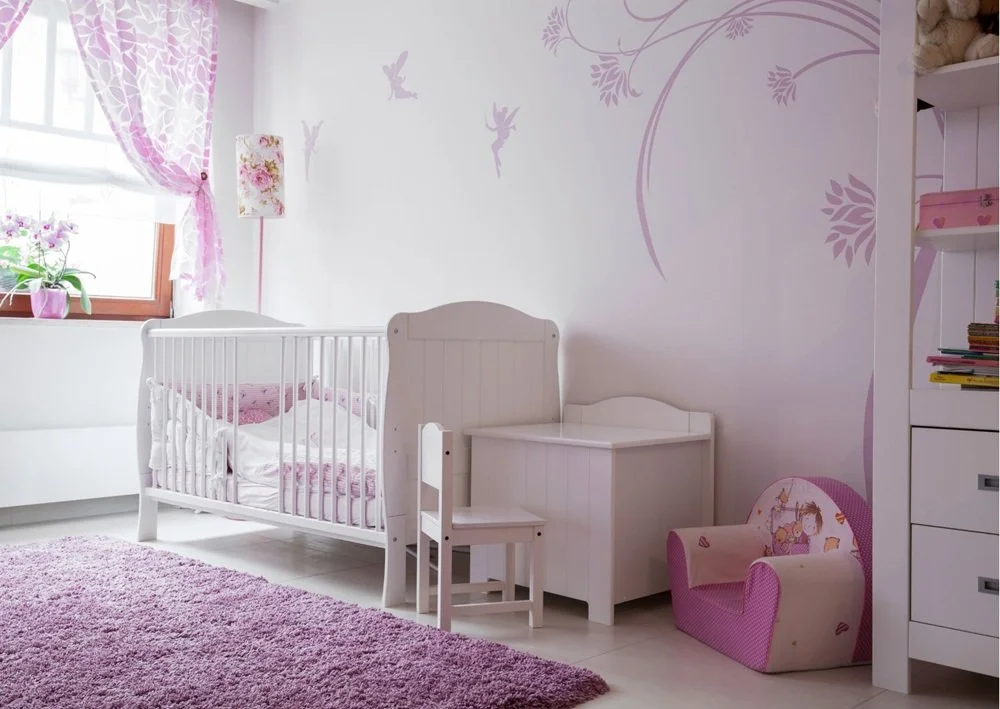 Soft pastel nursery room with crib, pink rug, floral curtains, and wall decals.
