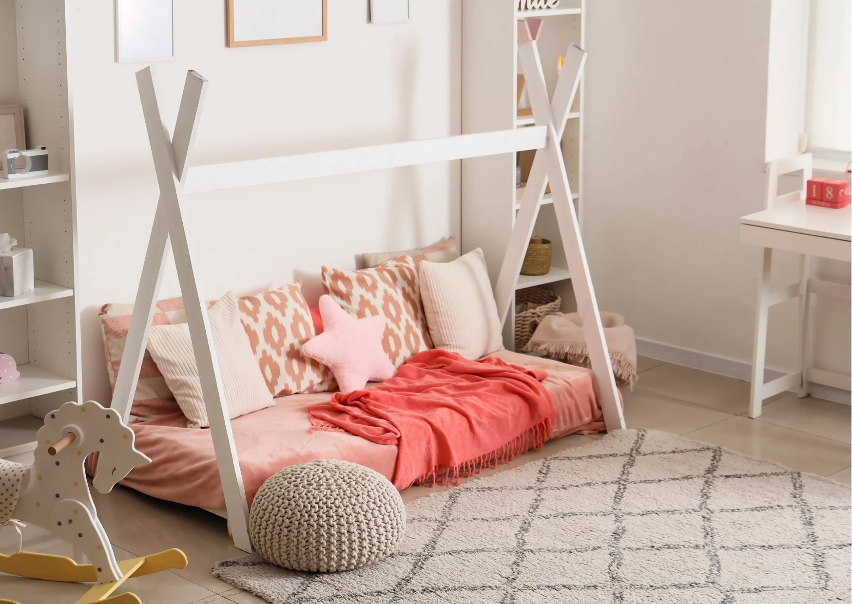 Cozy children’s room with teepee bed, pink bedding, rocking horse, and soft lighting.