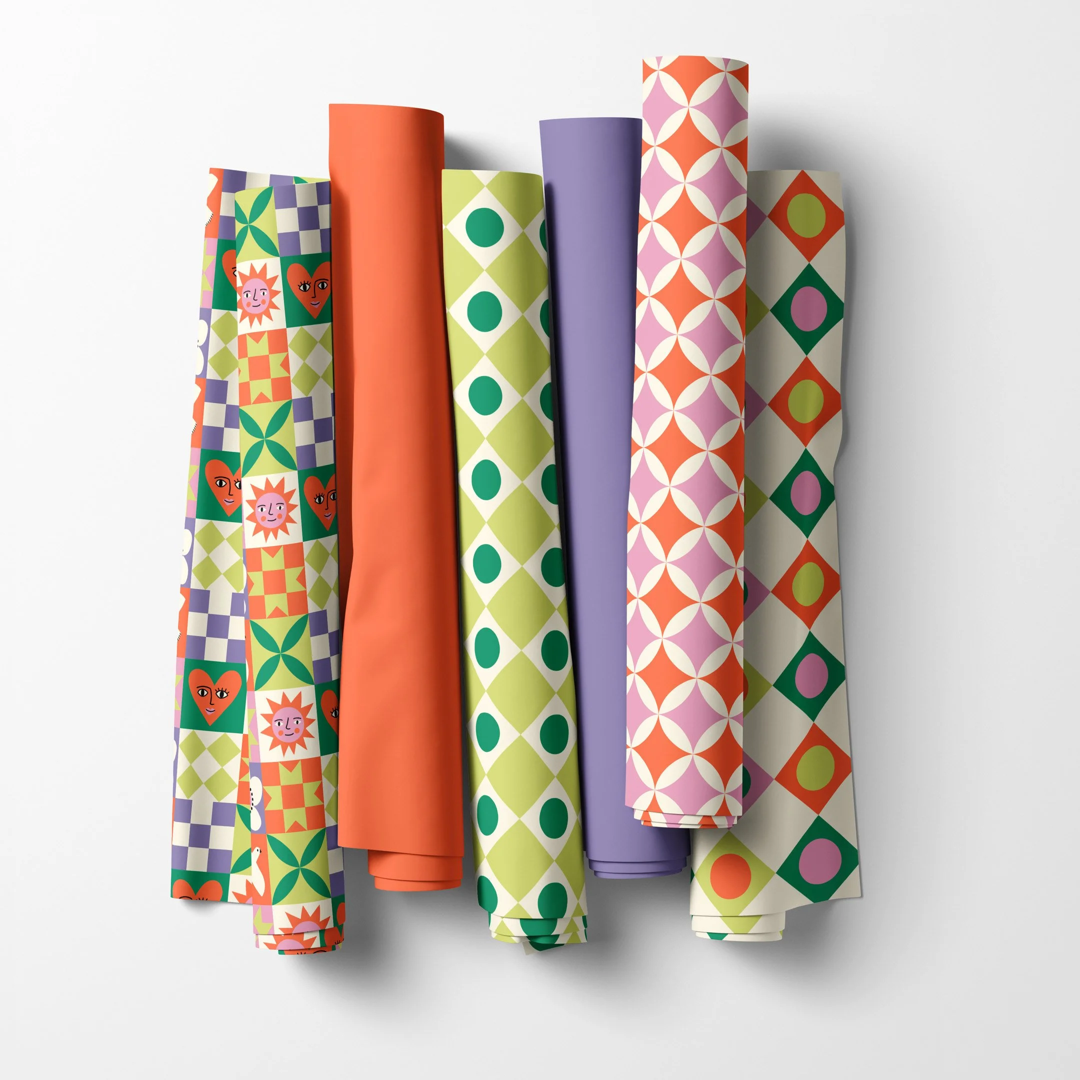 Happy Patchwork collection fabric rolls in patchwork quilt sampler, harlequin diamond and orange peel prints with tangerine and lavender solids, copyright Sandra Hutter.