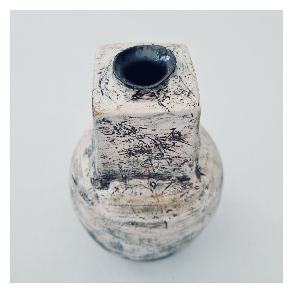 The opening of the vase has a metallic glaze detail which looks as if the vessel has been burst open.