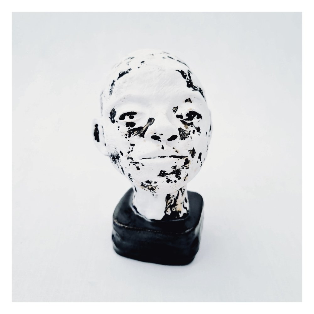 Expectations is a small black and white figure head mounted on a square ceramic base.