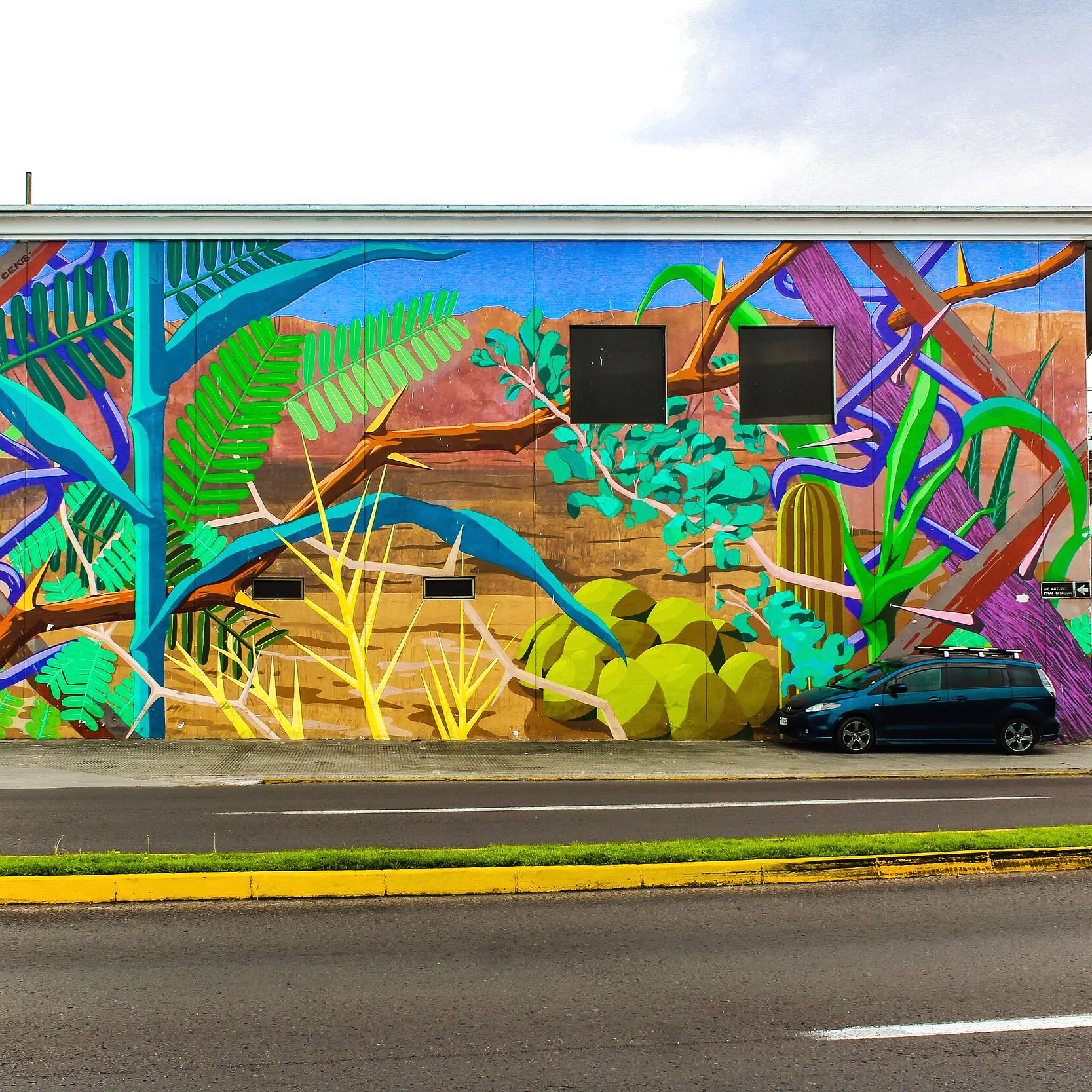 Colorful mural of jungle plants and twisted branches painted on the side of a building with a parked black car in front.