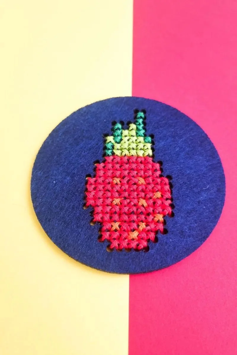 strawberry scross stitch felt coaster with purple background and cross stitched strawberry