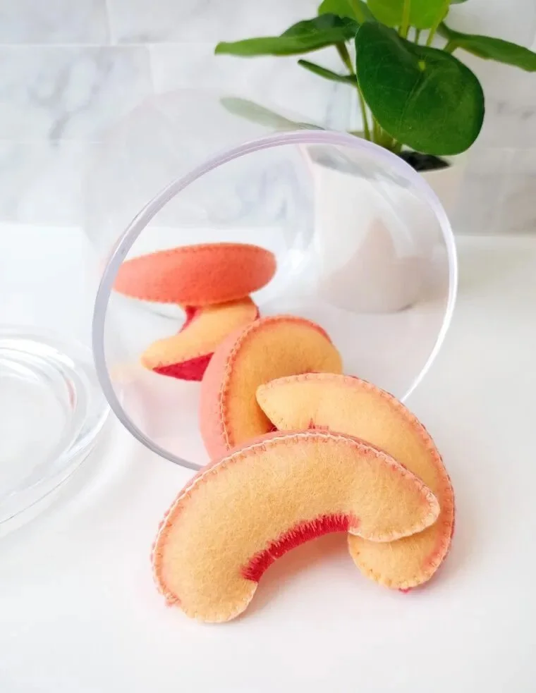 several felt peach slices in a glass bowl with felt free pattern