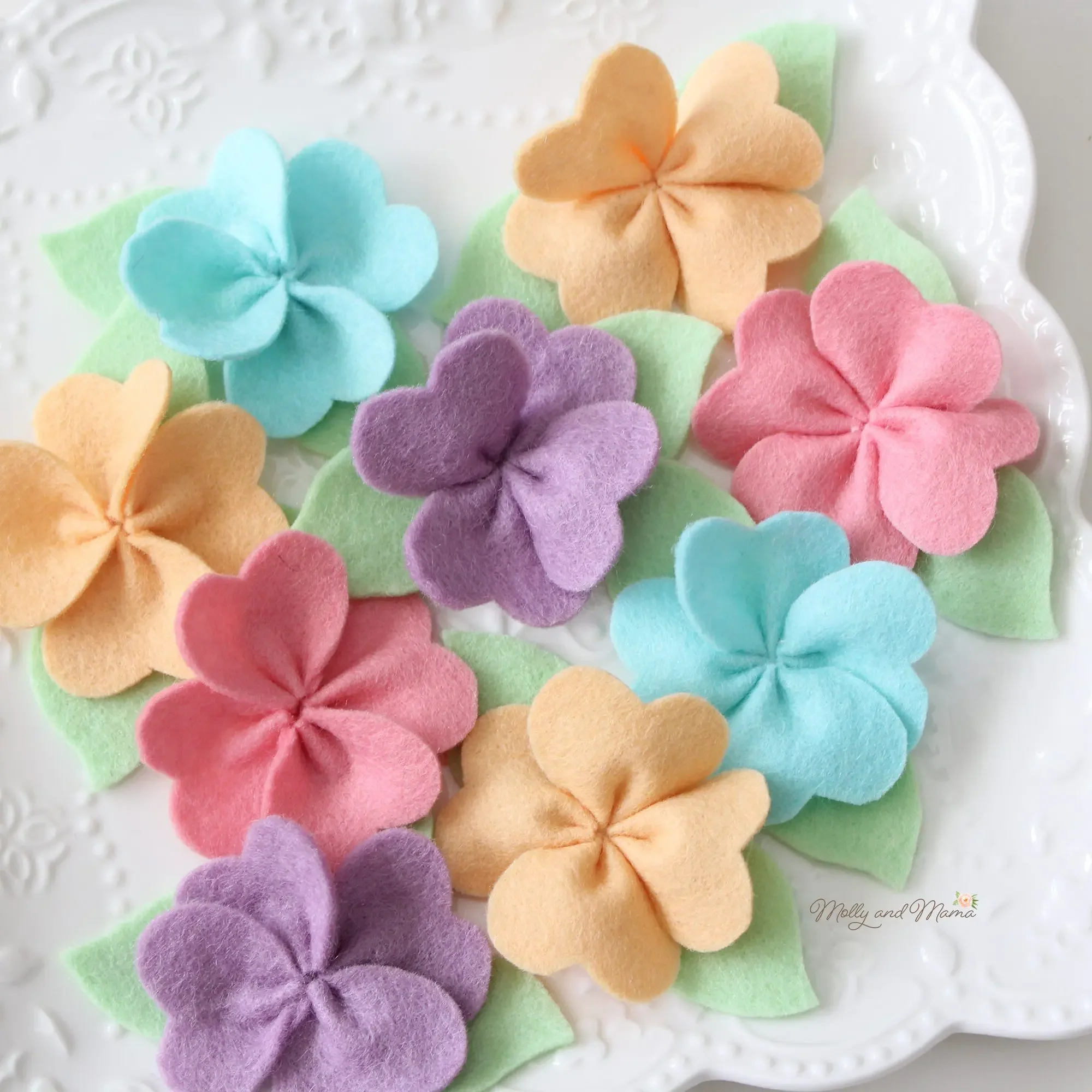 little felt flowers in pastel colours on a plate