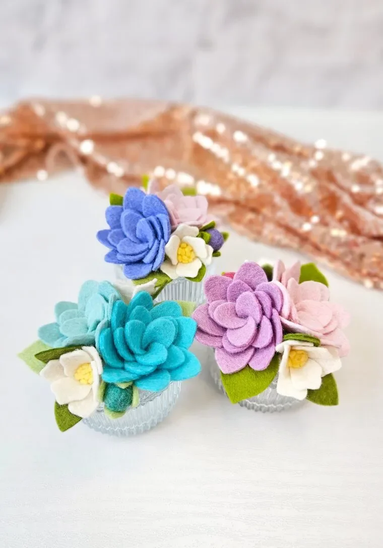 three mini flower arrangements from felt placed on a table