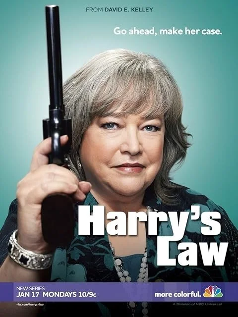 Close-up of a woman with short gray hair holding a handgun, with text promoting the TV series "Harry's Law" and the NBC logo.