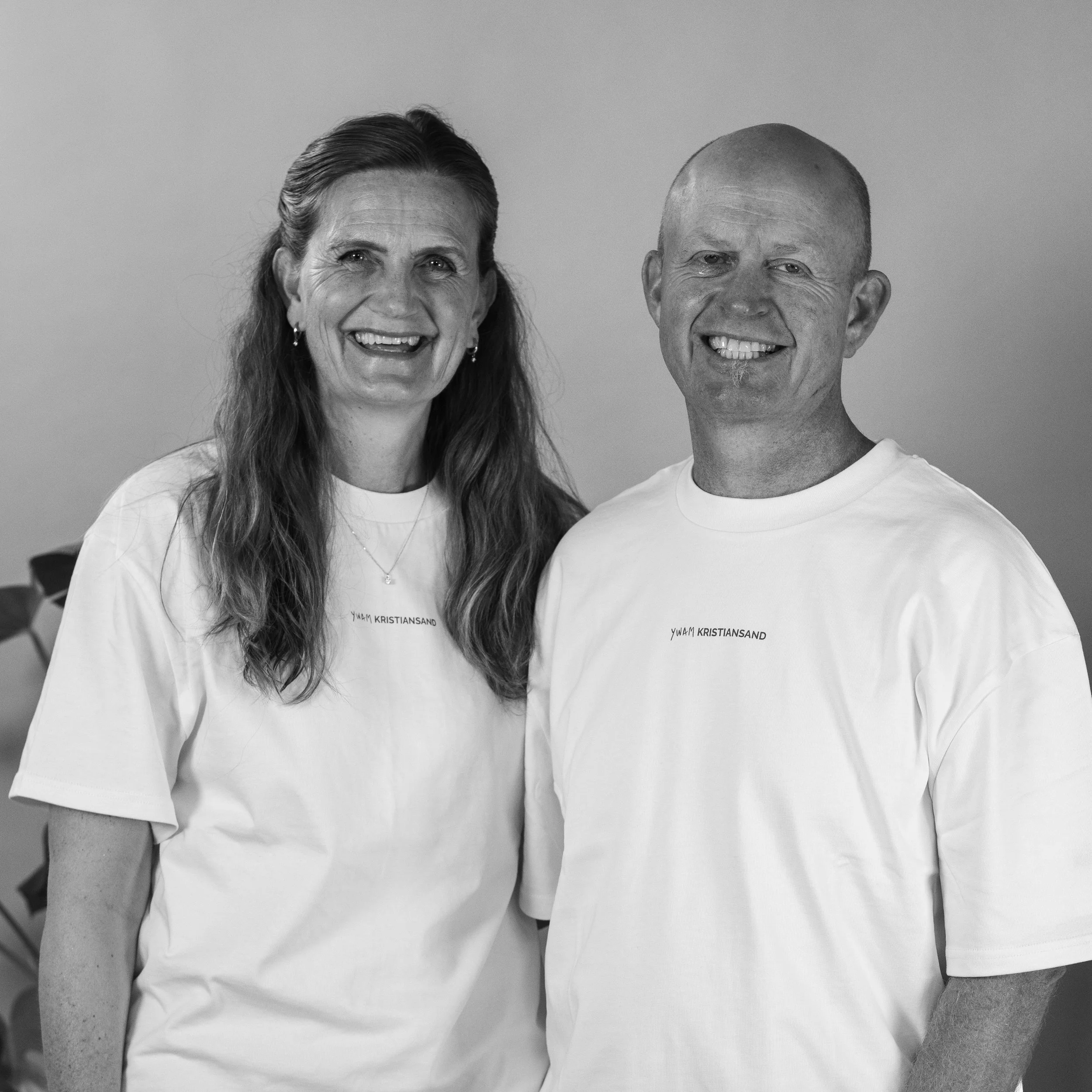 Grayscale photo of a smiling woman with long hair wearing a white shirt and necklace.