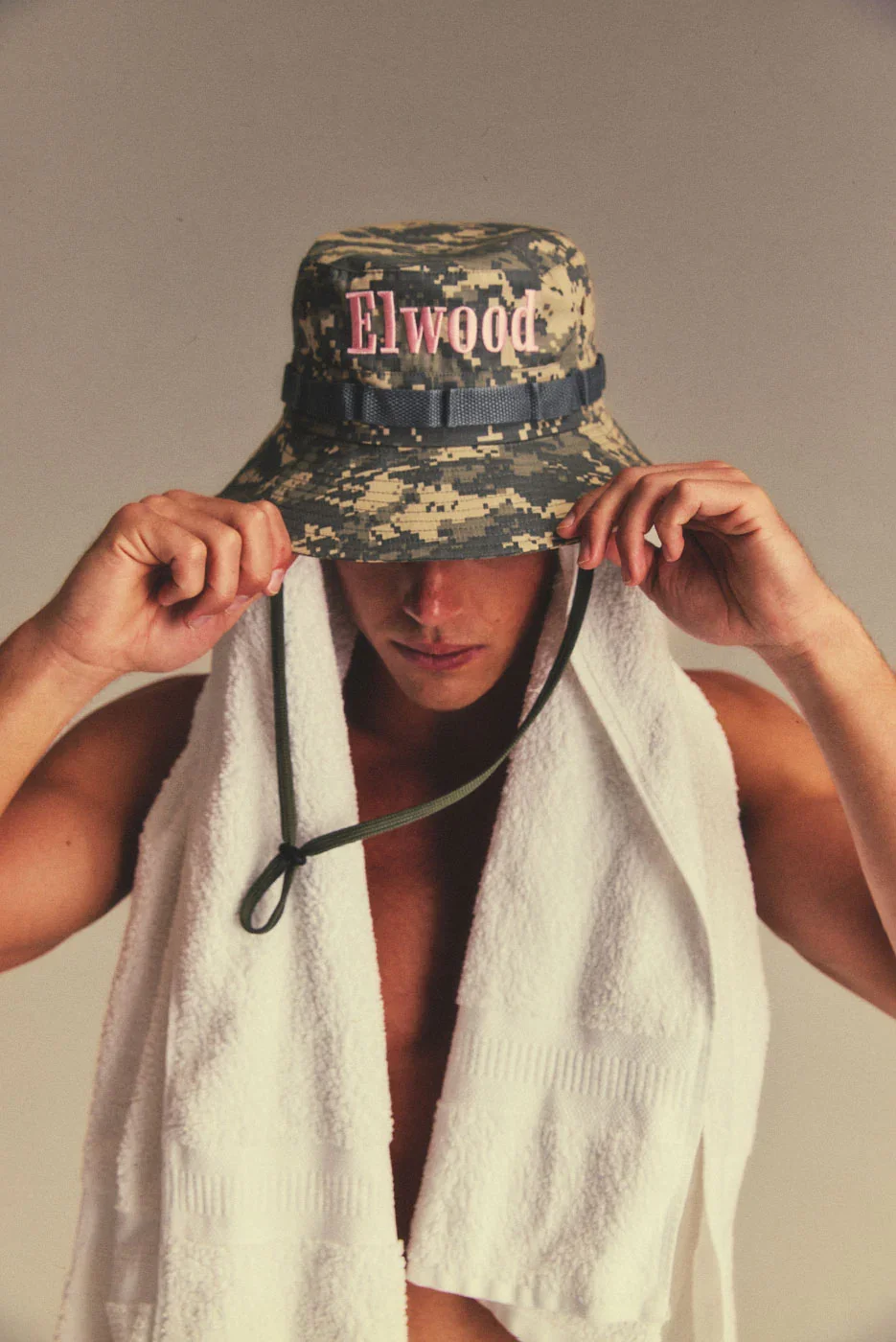 A digital camo bucket hat with baby pink Elwood embroidery and textured webbing. Secured with an adjustable toggle and drawcord.