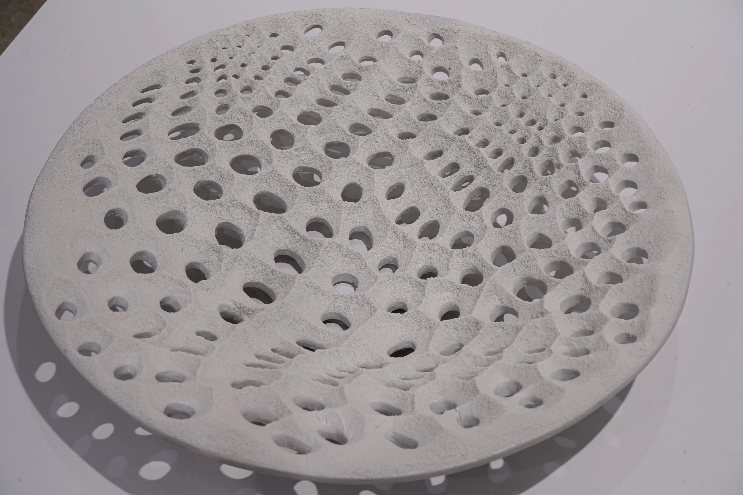 Ceramicology exhibit showing a white circular sculpture with holes