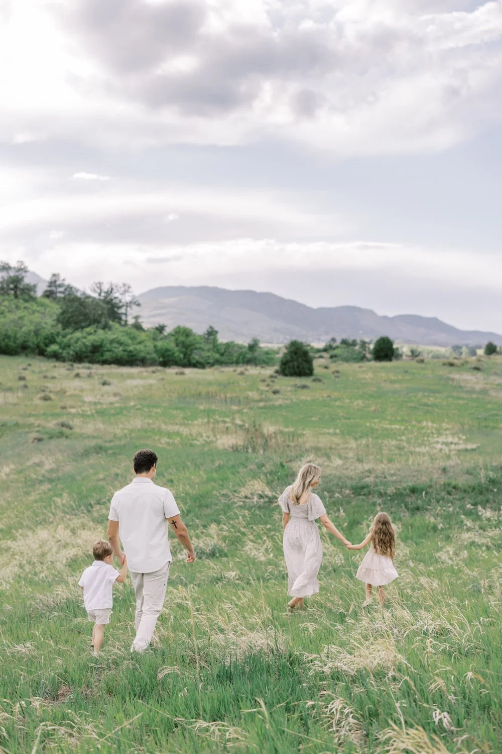Colorado family walking through green pastures in mountains