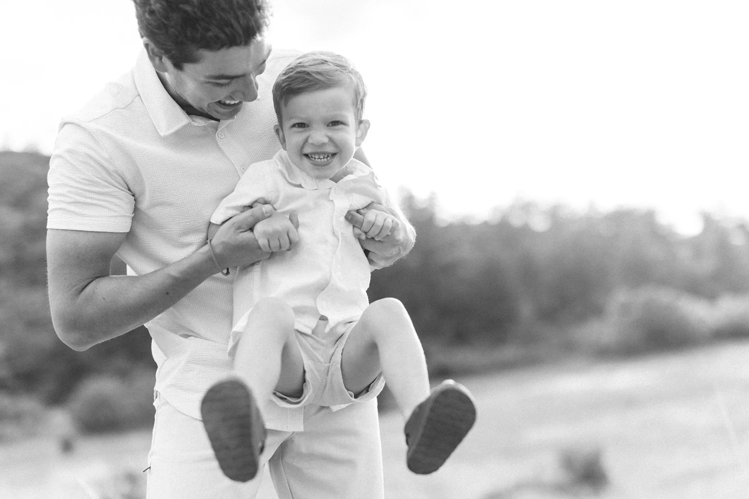 father playing with son black and white photo