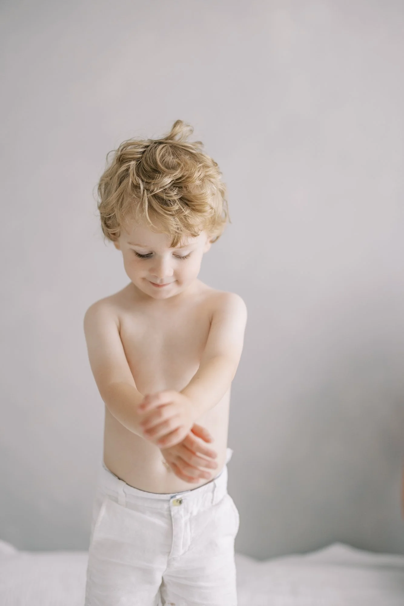 Portrait of a curly-haired toddler during a family newborn photography session.