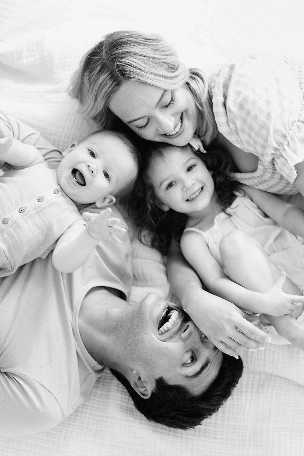 Black and white portrait of parents laughing and cuddling with their young children