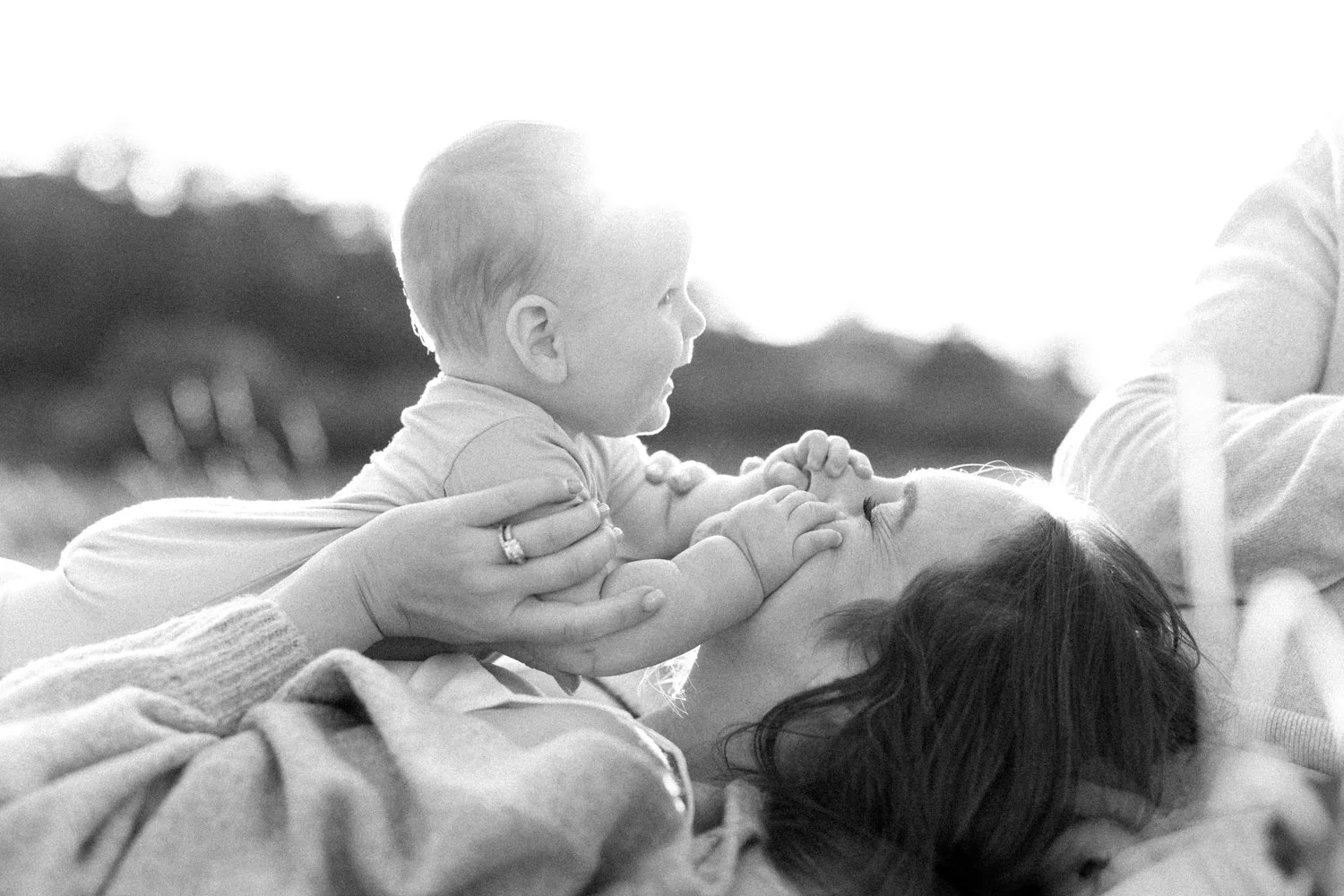 Baby happily grabbing mom nose in family portrait