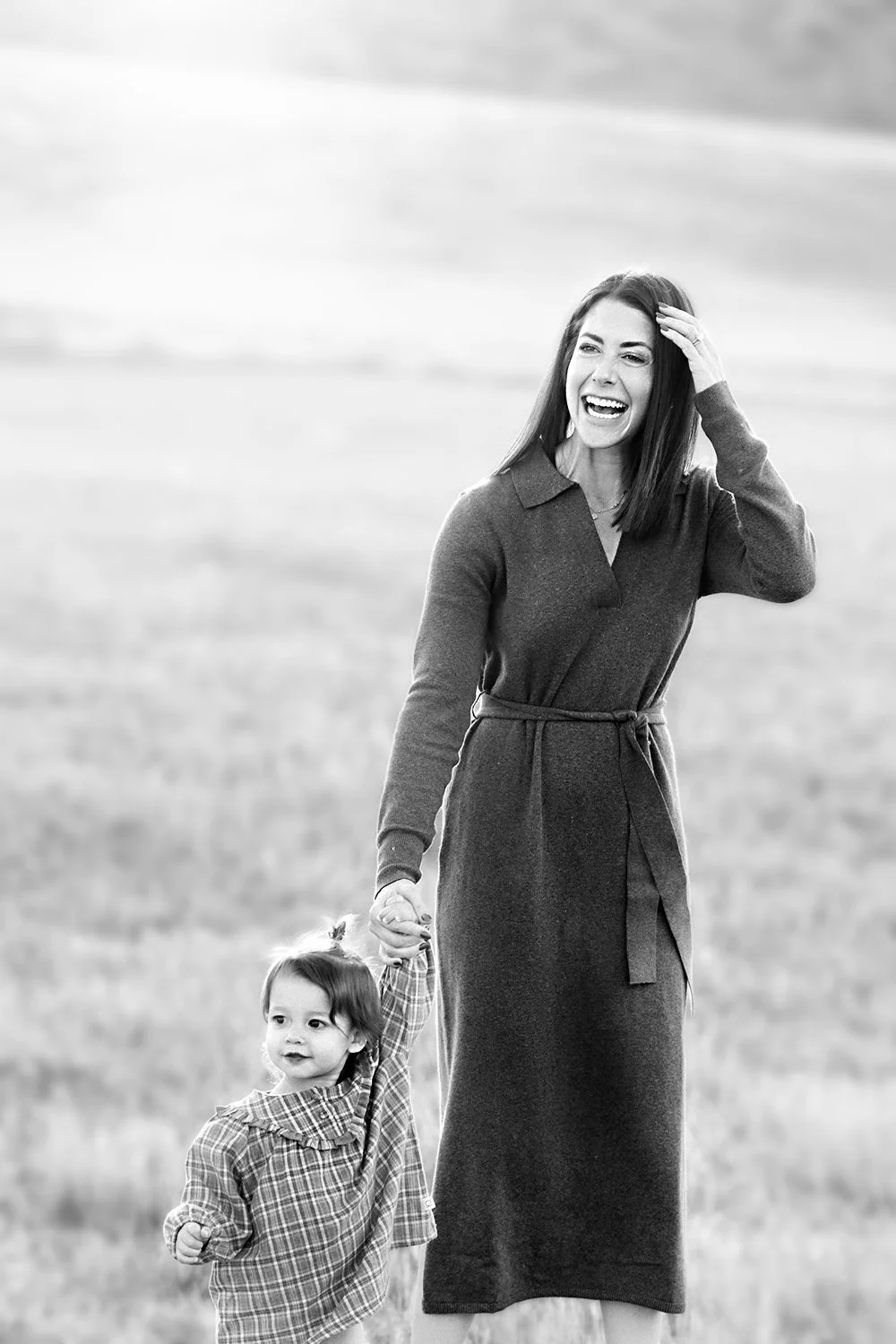 Candid black and white of mom walking with young daughter in a field