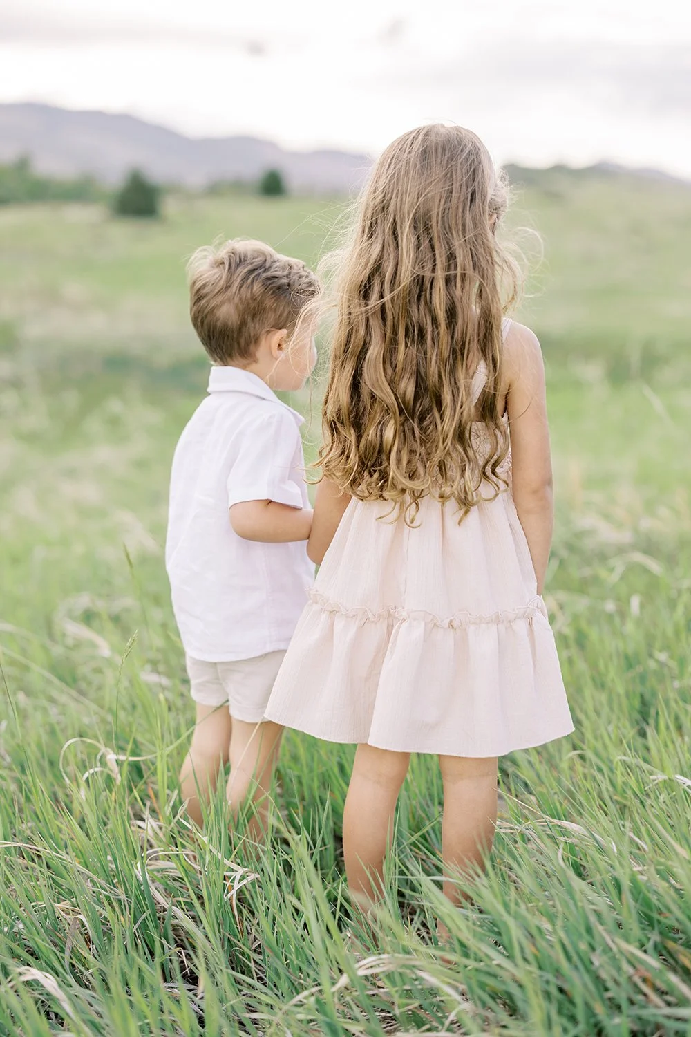 Brother and sister walking together through a grassy Colorado field