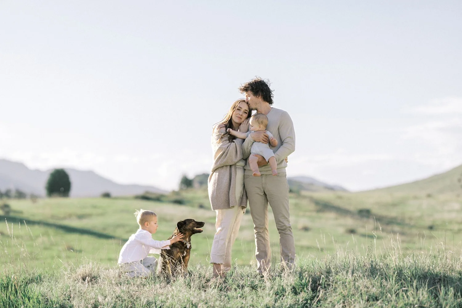 Dad kissing mom on forehead during family portrait in Colorado hills