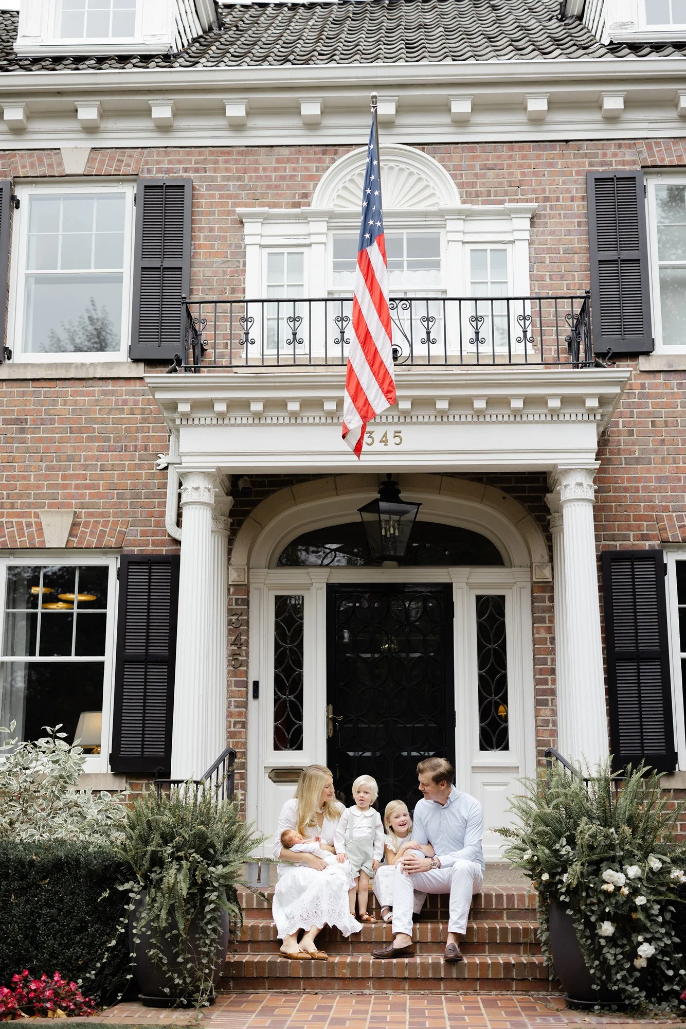 Parents and children sitting together outside their home during a lifestyle newborn session.