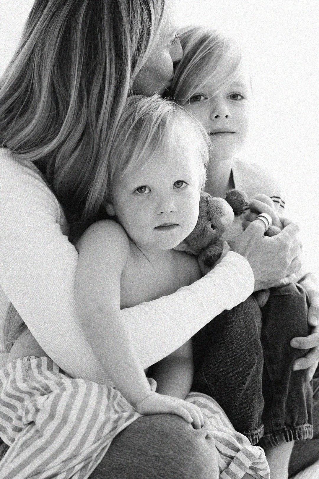 Black and white portrait of a mother cuddling her two young children