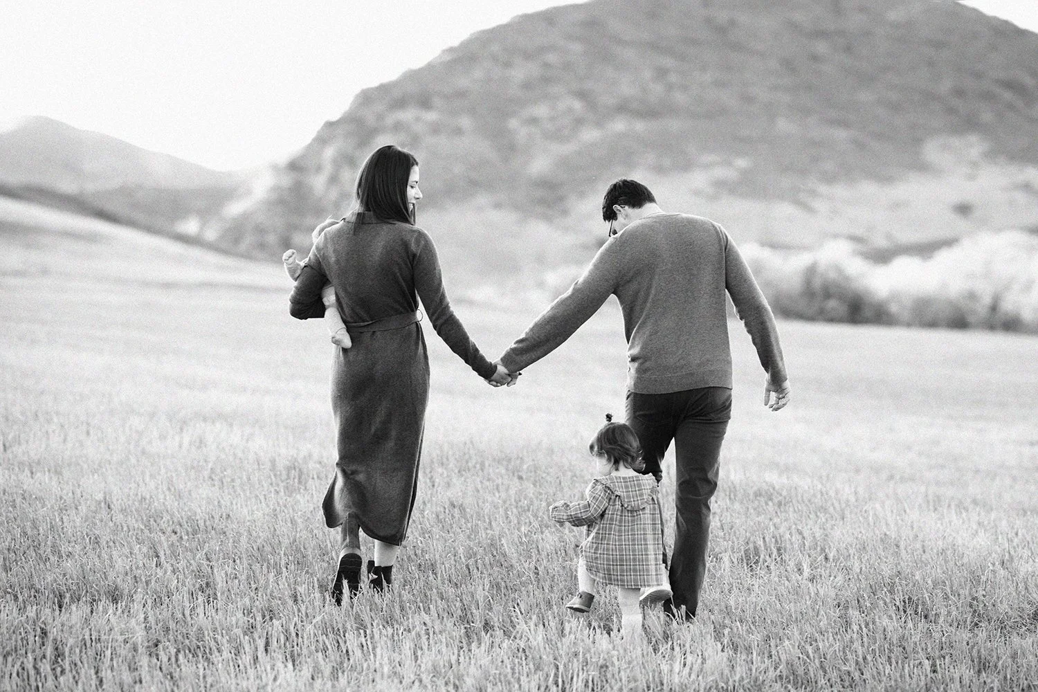 Parents walking hand in hand with their children through an open Colorado field in black and white.